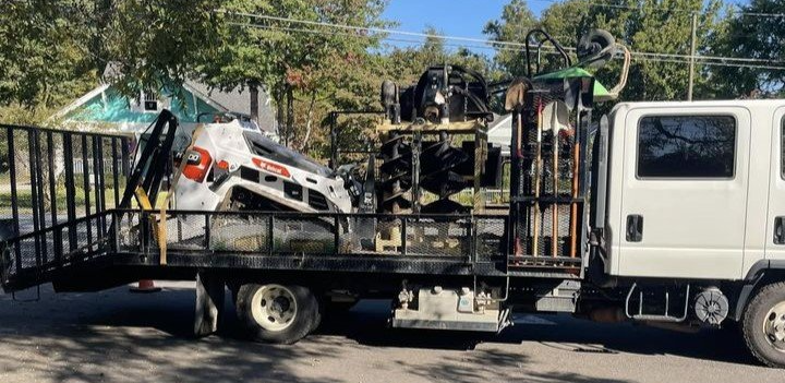 A tow truck with a tractor on the back is parked on the side of the road.