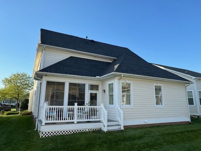 White house with dark roof and small front porch on a sunny day