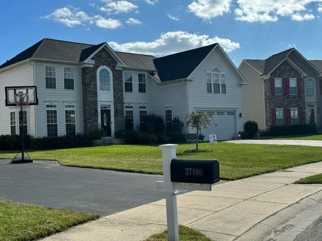 Suburban house with driveway, front lawn, and black mailbox under a clear sky