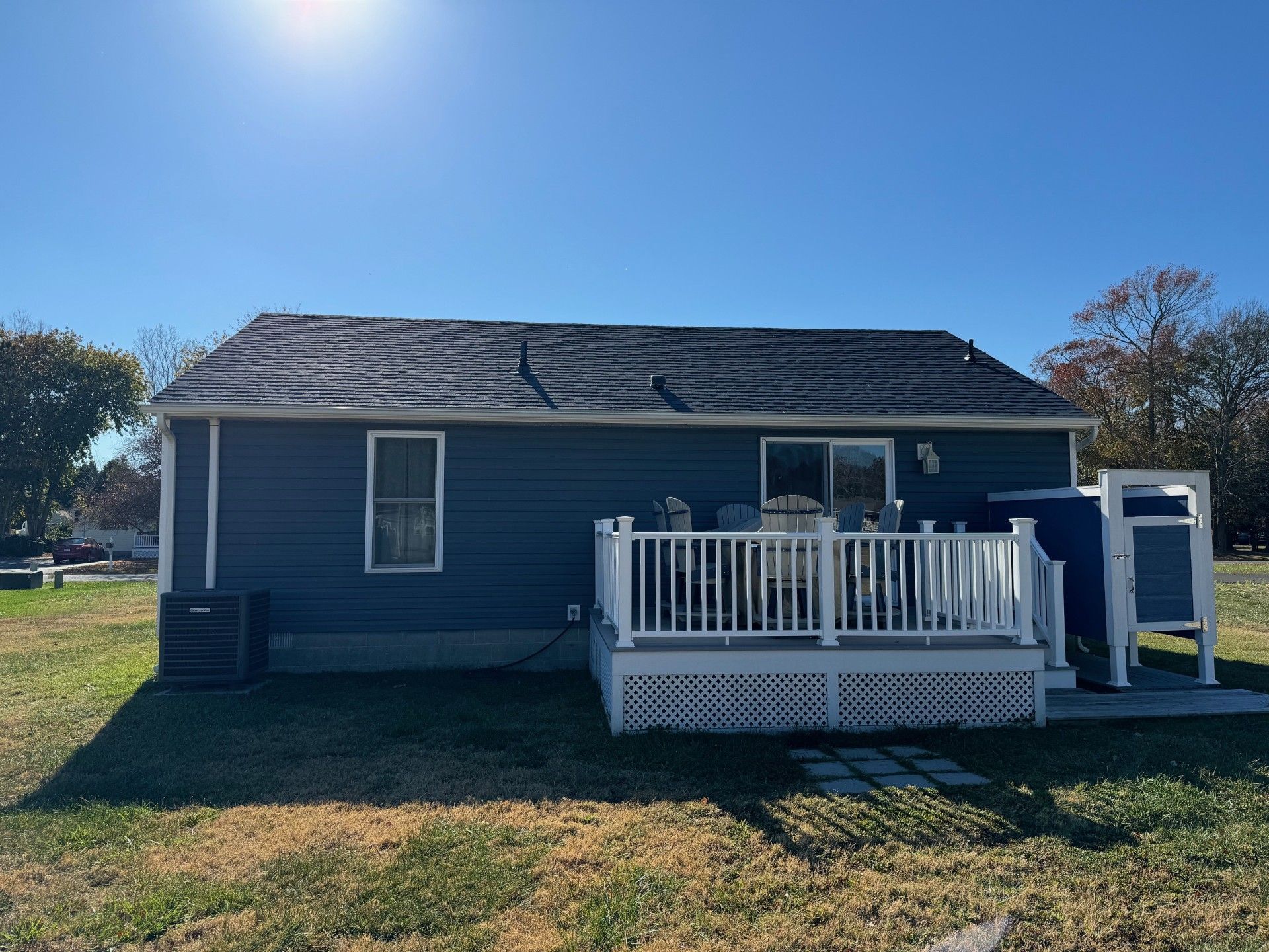 Blue house with a small white deck and ladder in a sunny yard.