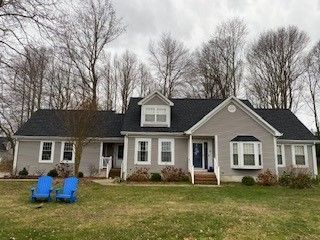 Single-story gray house with white trim and two blue chairs on the front lawn