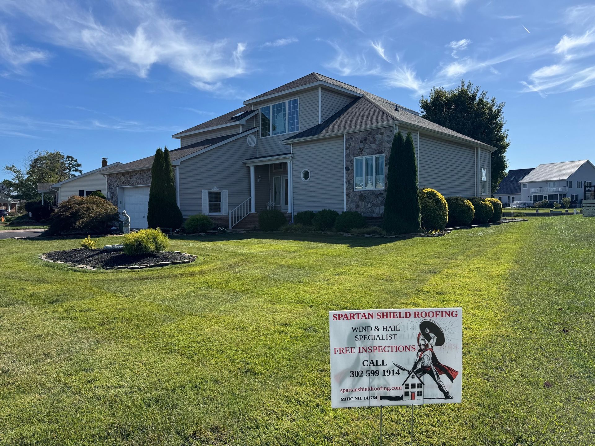 House with “For Sale” sign on a sunny lawn under a blue sky