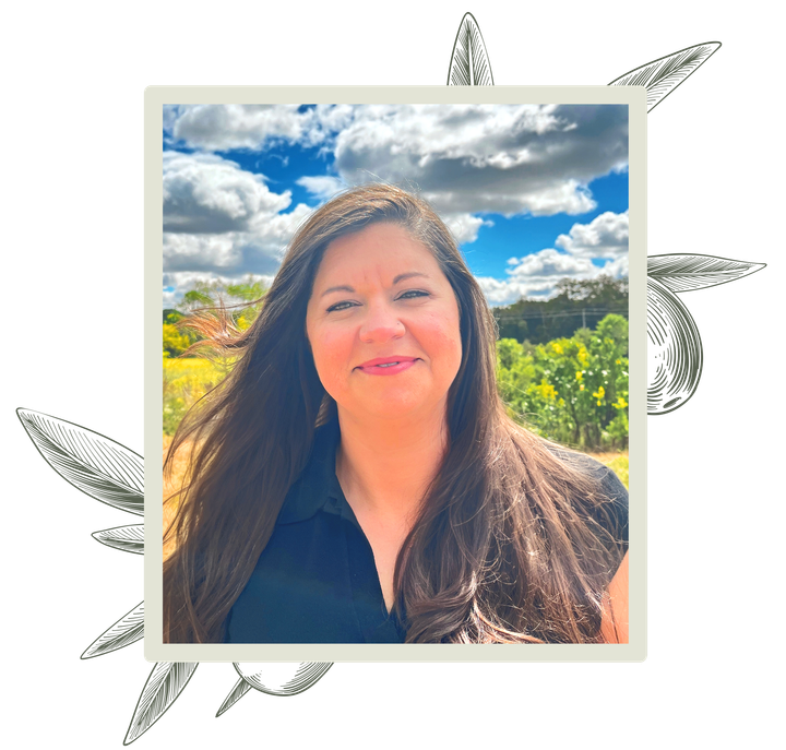 Woman with long dark hair smiles outdoors, framed by stylized olive branch.
