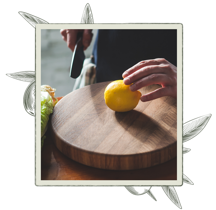 Lemon on wooden cutting board, hand holding knife.