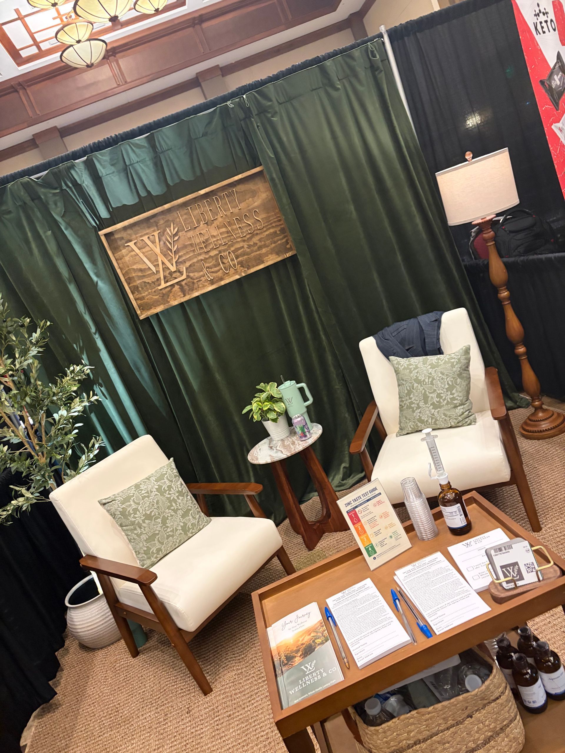 Cozy lounge with two cream chairs, wooden coffee table, green curtains, and warm lighting