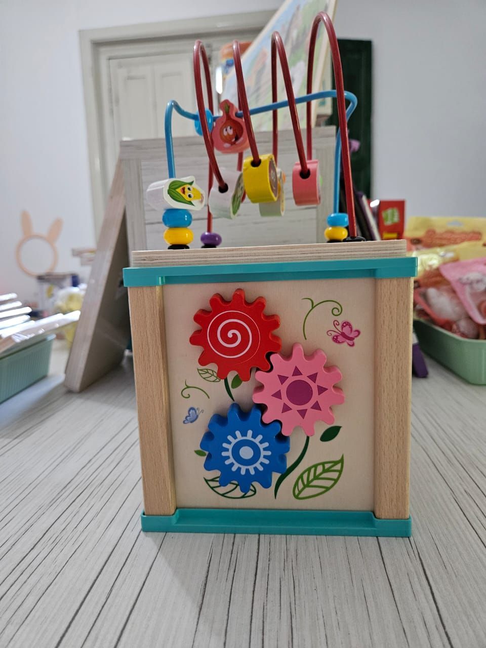 Cubo de actividades de madera con temática de búho, con laberinto de cuentas en la parte superior, colocado sobre una mesa.