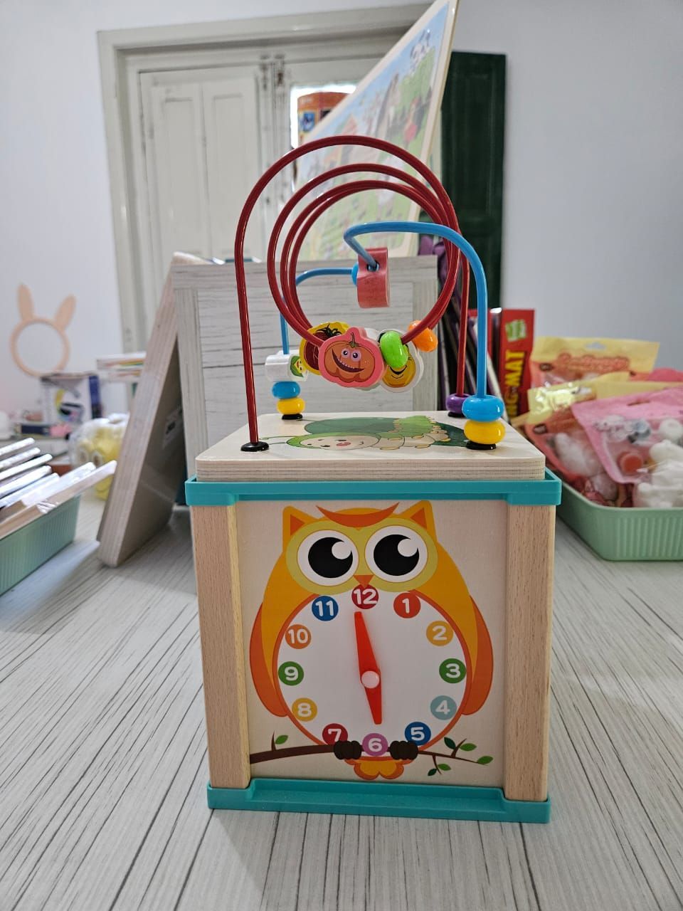 Cubo de actividades de madera con temática de búho, con laberinto de cuentas en la parte superior, colocado sobre una mesa.