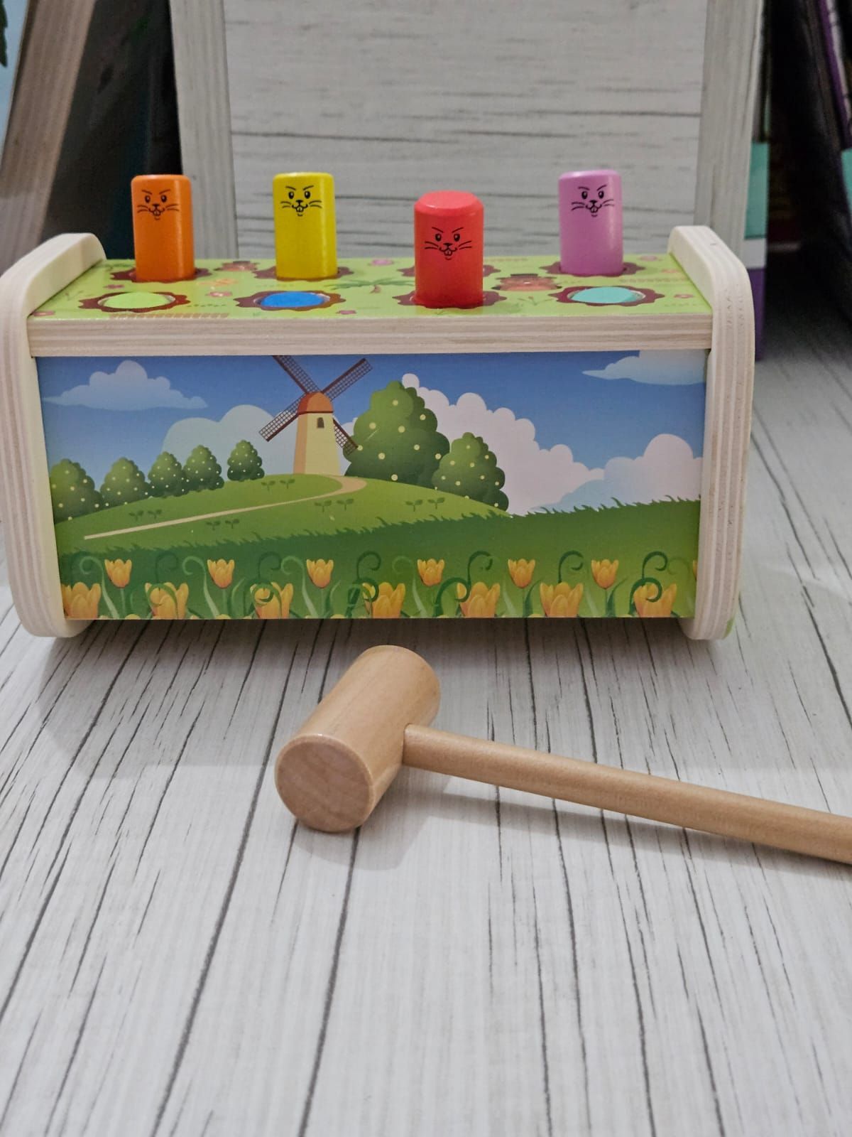 Juguete de madera para golpear con clavijas de colores y martillo, escena de paisaje holandés.