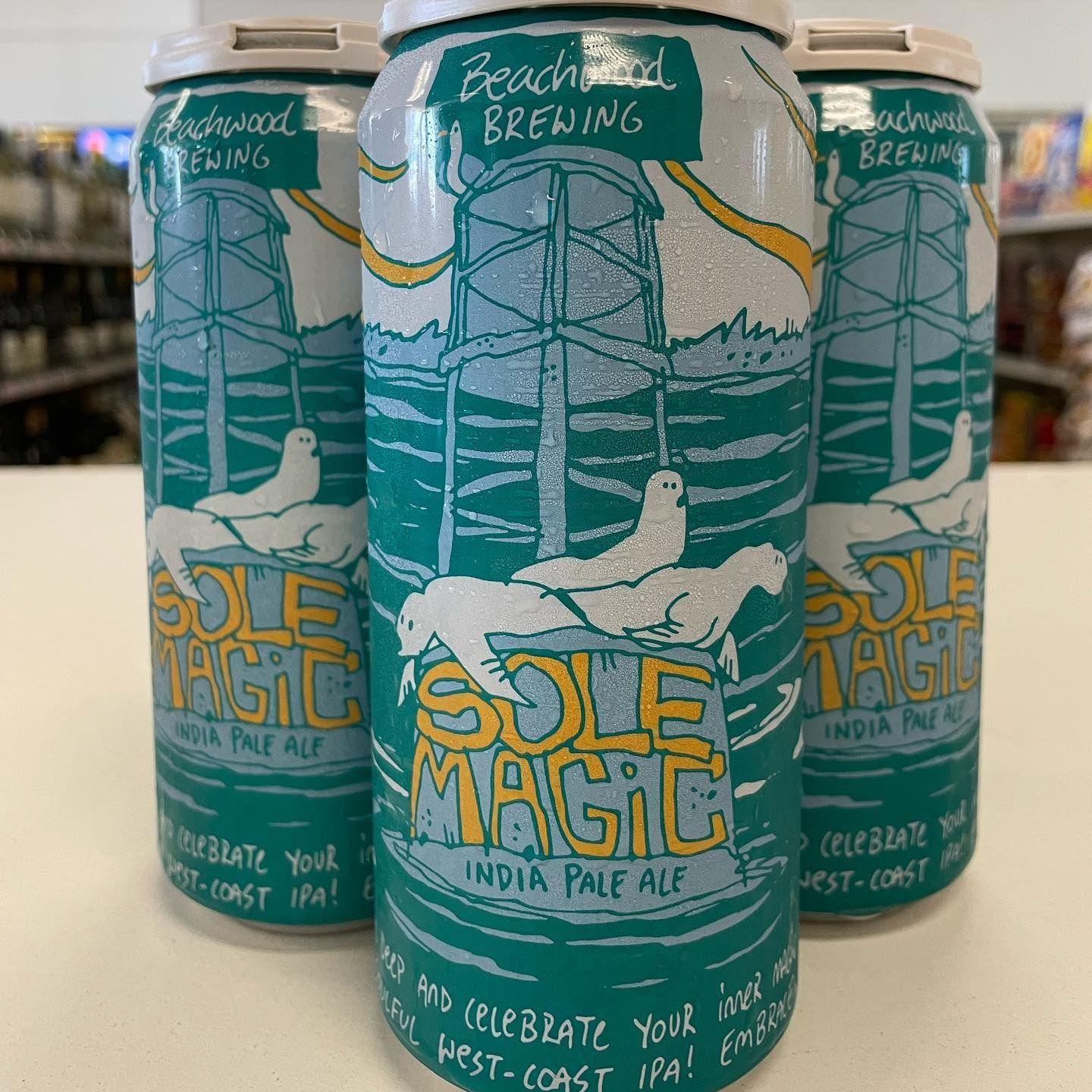 Four cans of "Sole Magic" India Pale Ale, featuring a teal design with seals and a water tower.