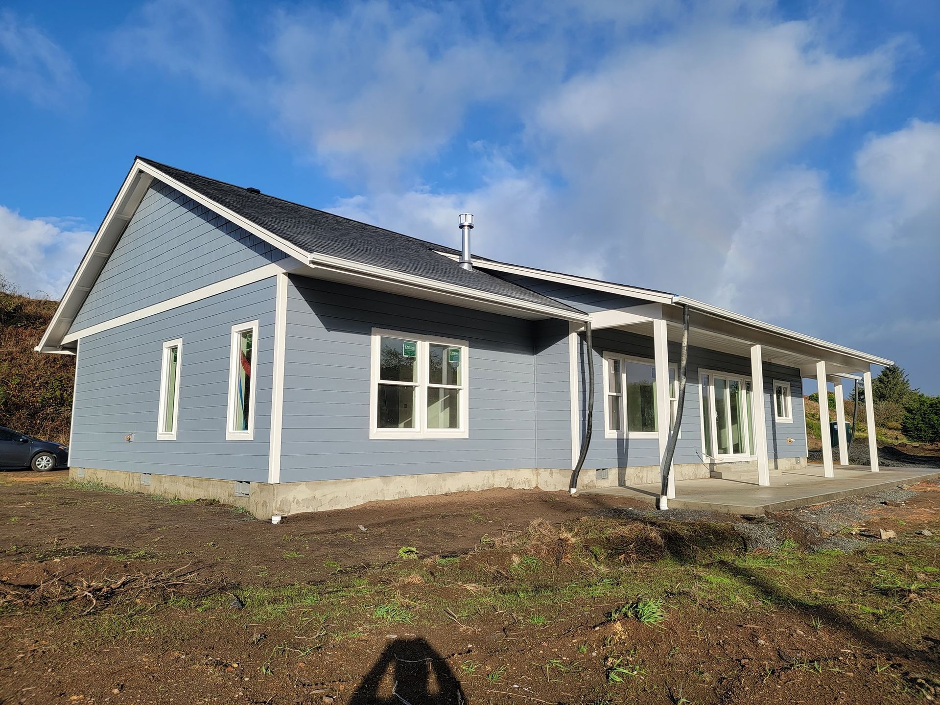 A gray house with a porch and a blue sky in the background
