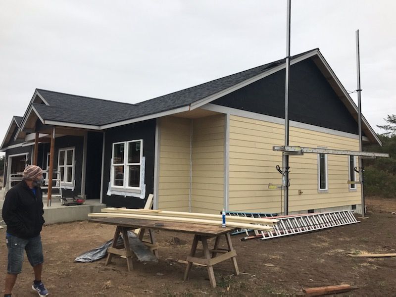 A man is standing in front of a house under construction.