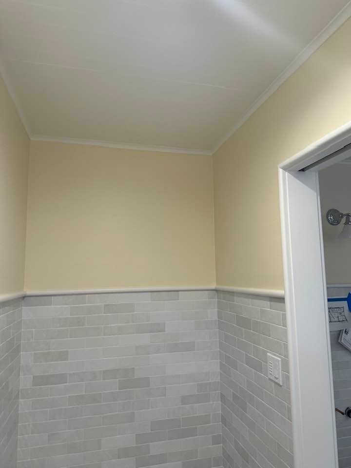 A bathroom with white tile walls and a white door.