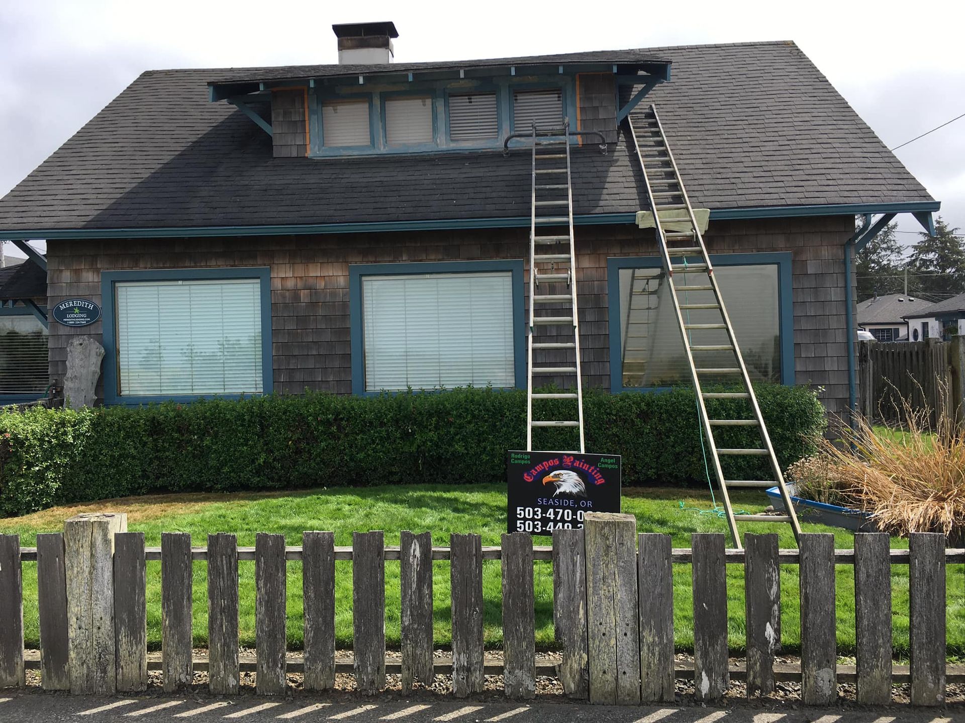 A house with a wooden fence and a ladder on the roof