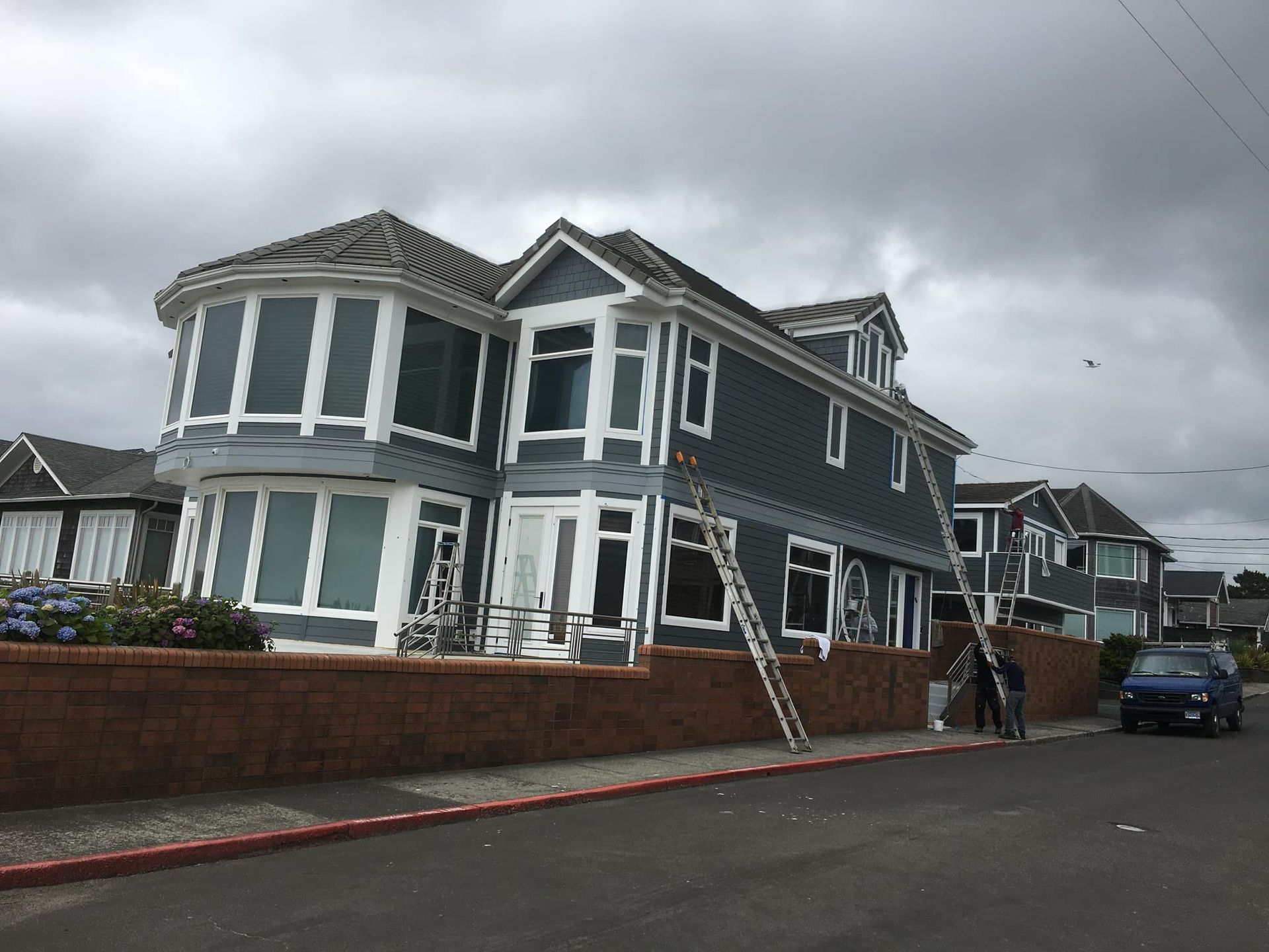 A large house is being painted on a cloudy day.