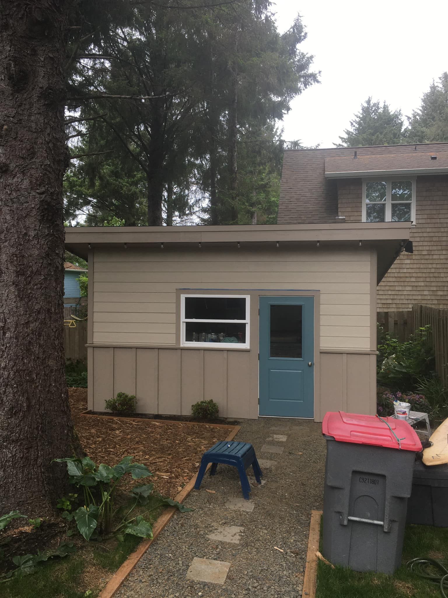 A small house with a blue door and a blue stool in front of it