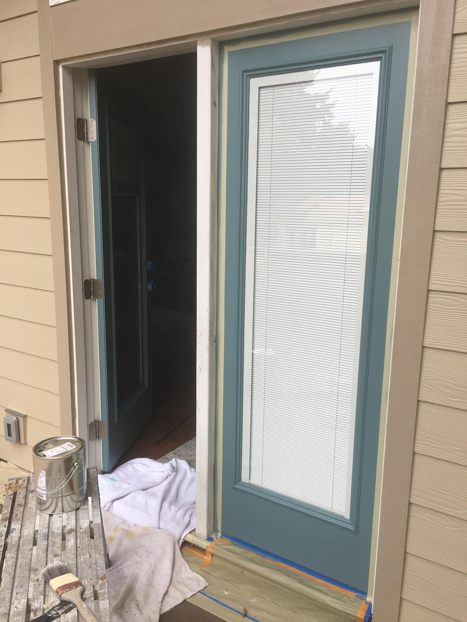 A blue door is being painted on the side of a house.