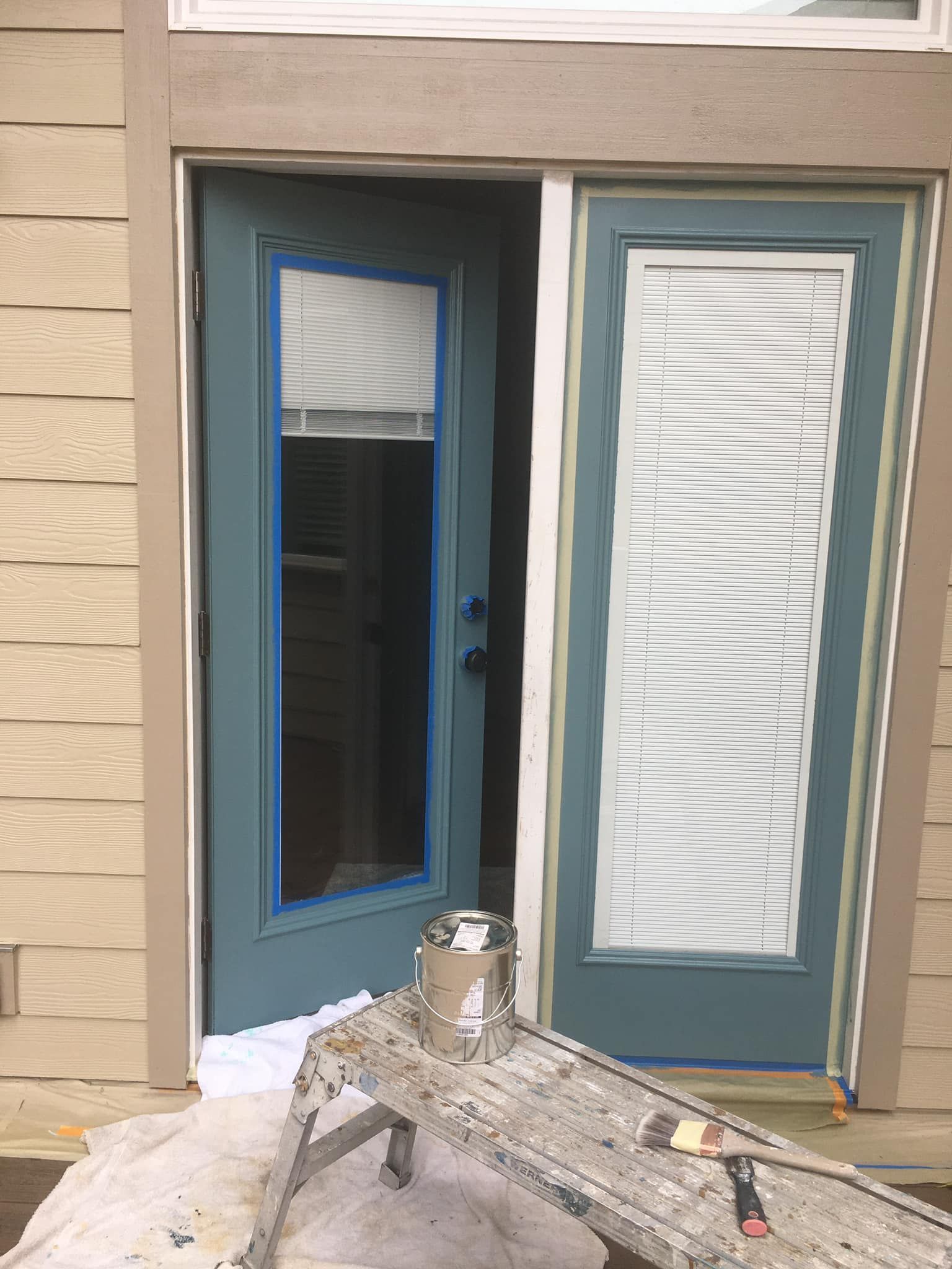 A blue door is being painted on a house.