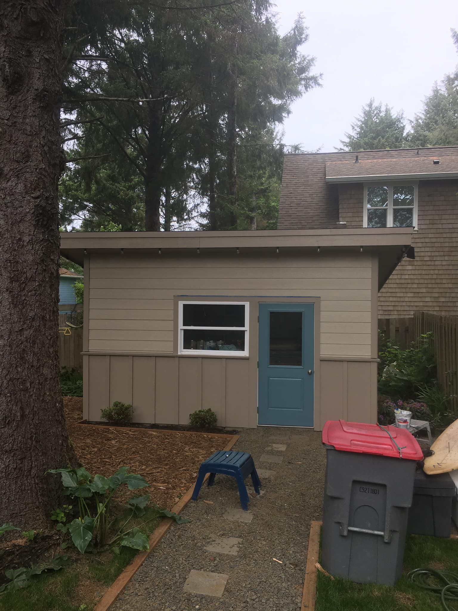 A small house with a blue door and a blue stool in front of it