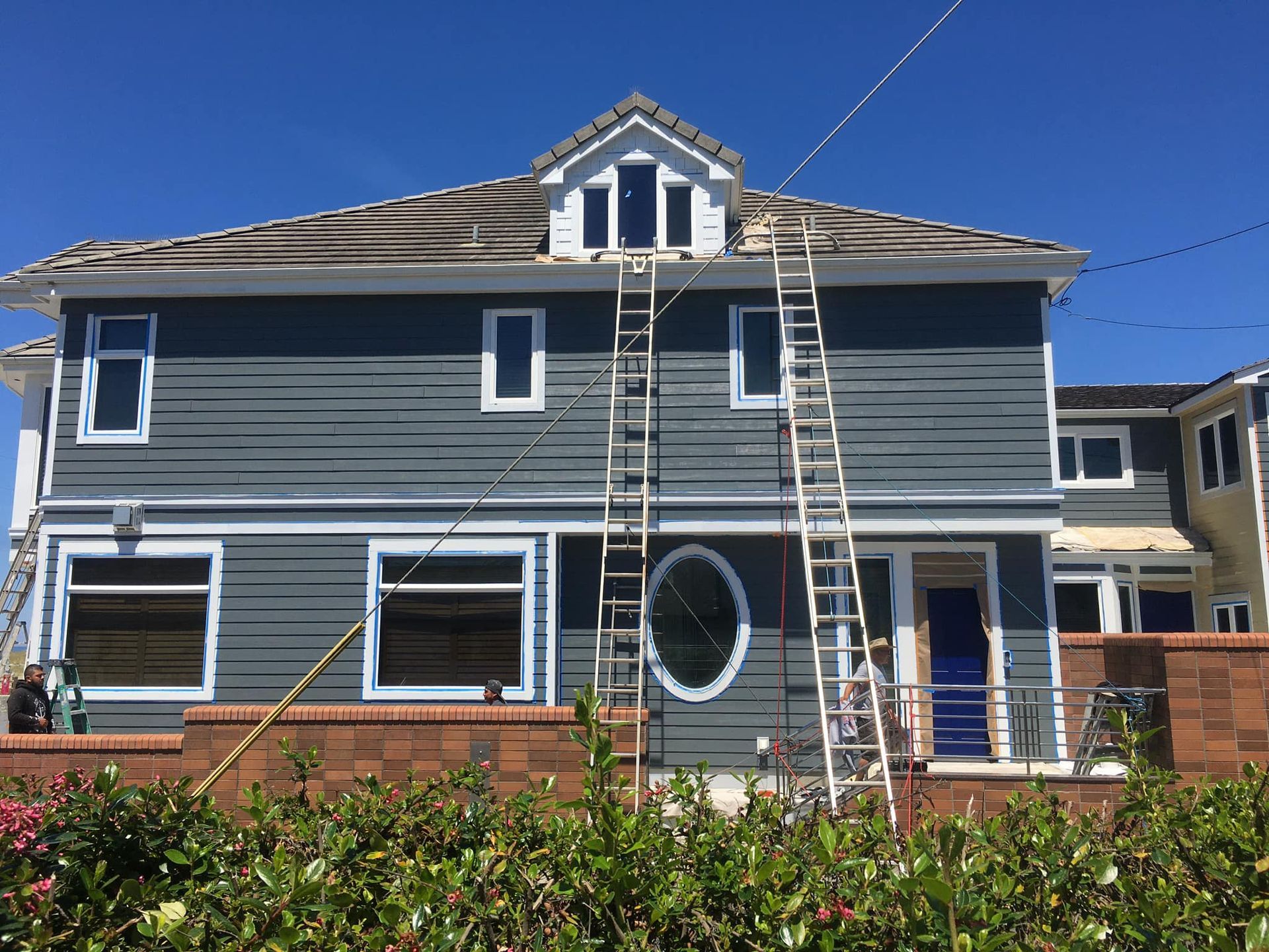 A house with a ladder on the side of it is being painted.