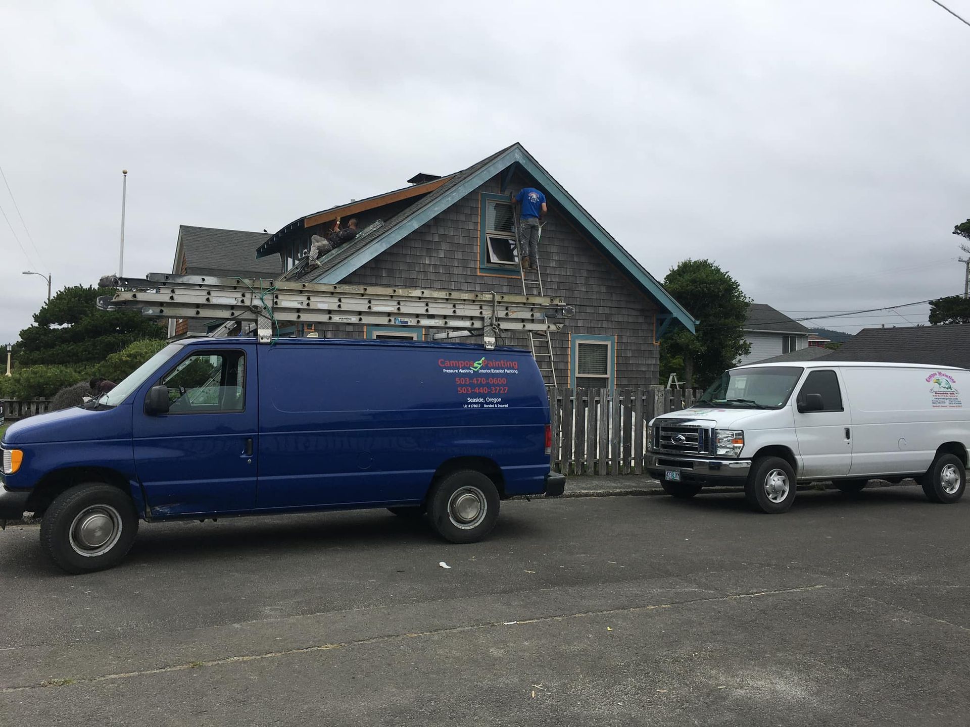 Two vans are parked in front of a house.