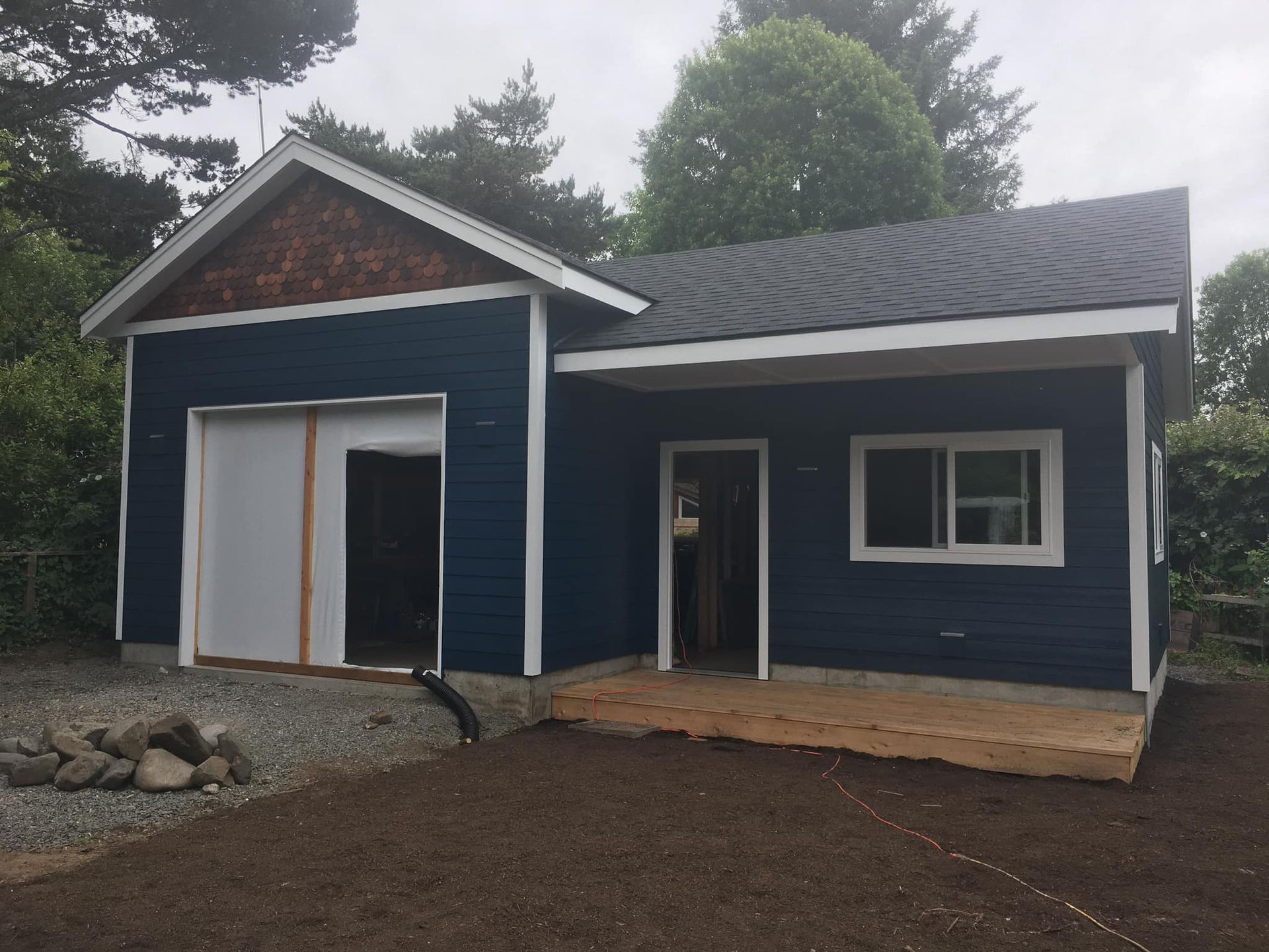 A blue house with a garage underneath it