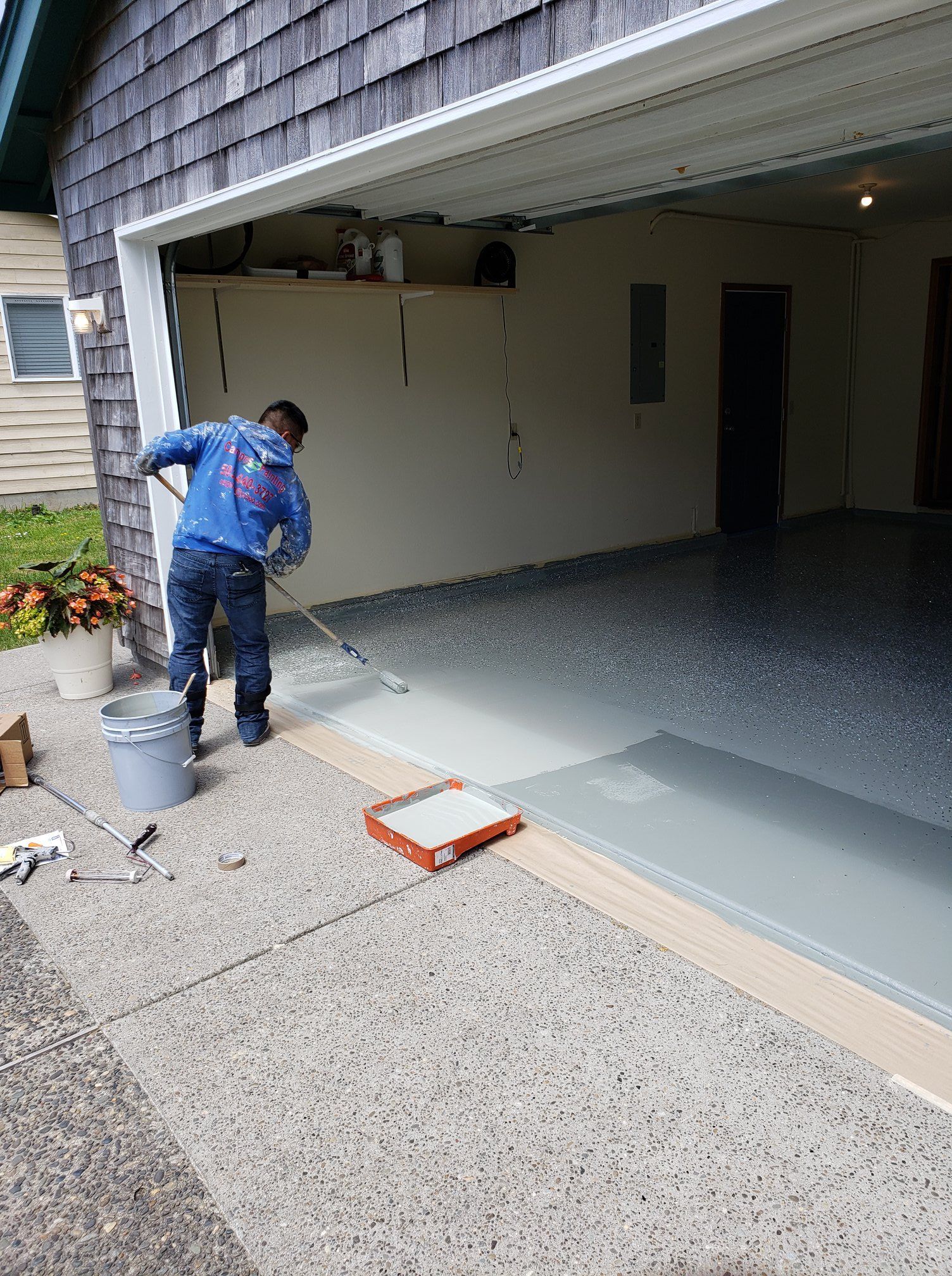 A man is painting the floor of a garage.