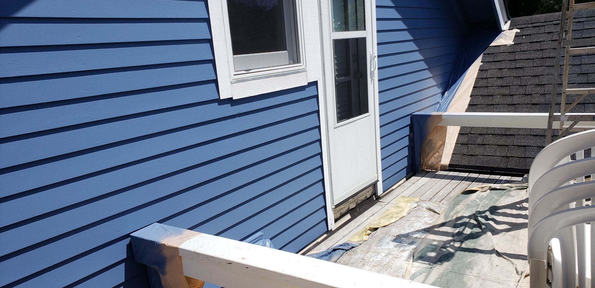 A blue house with a white railing and a white door
