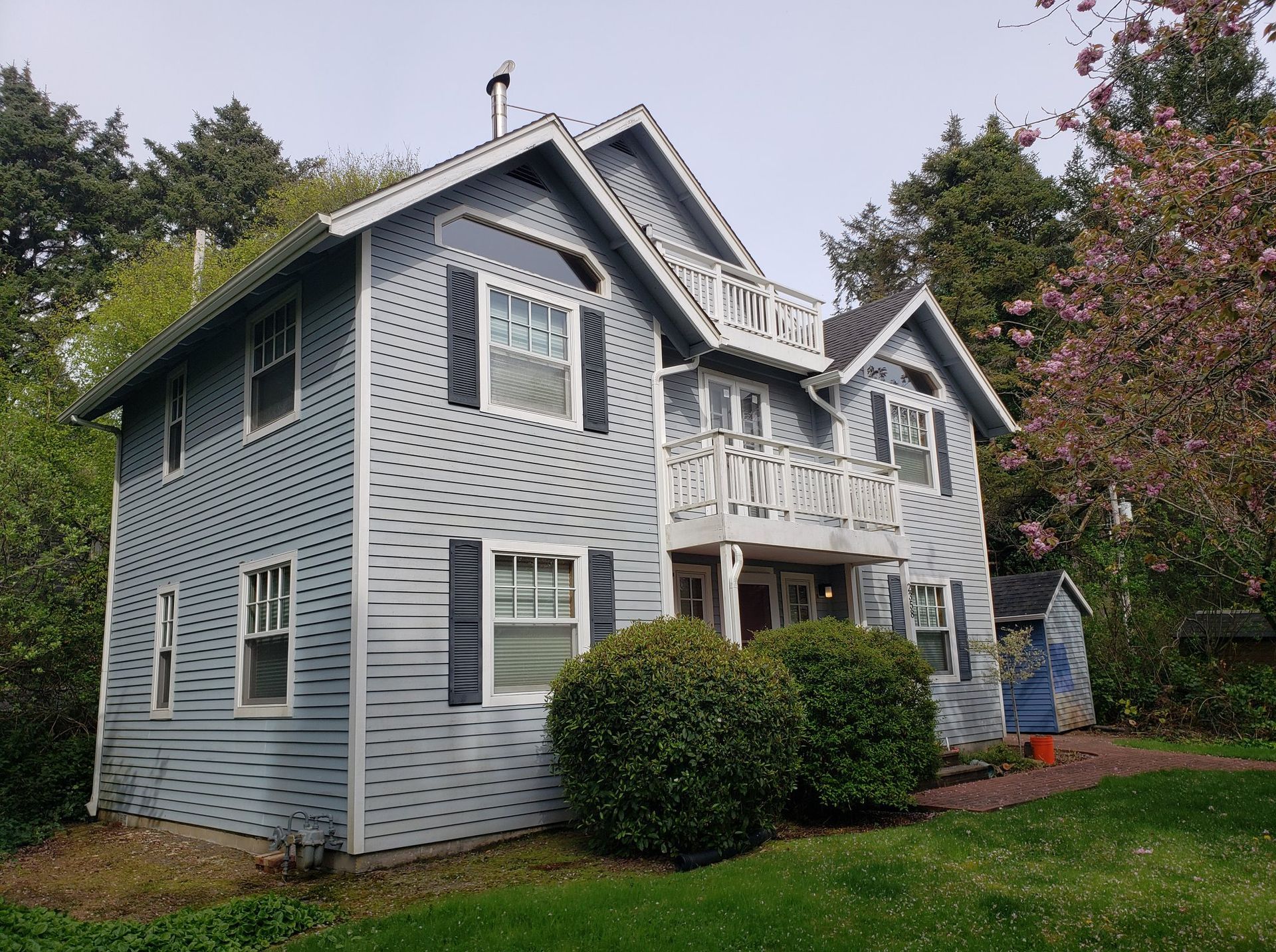 A large house with a lot of windows is surrounded by trees and bushes.