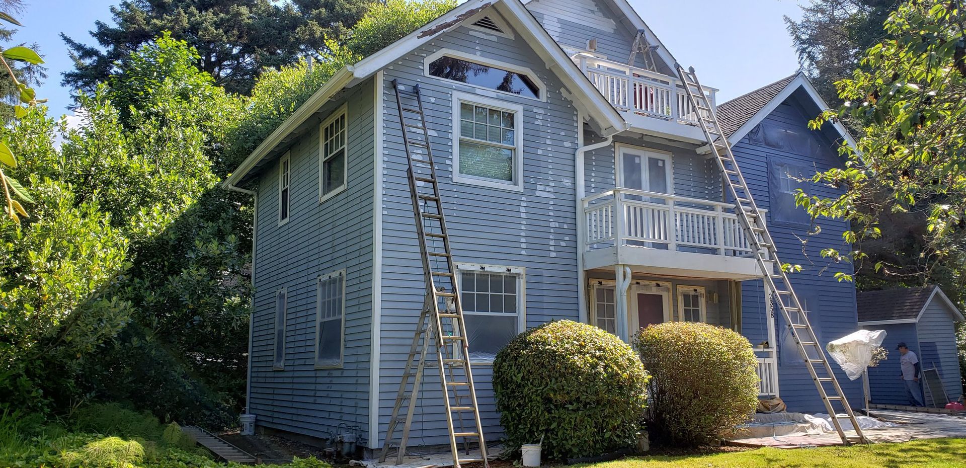 A blue house with a ladder on the side of it.