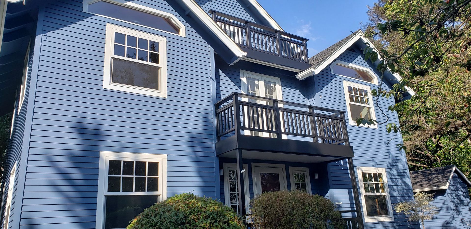 A large blue house with a balcony and lots of windows