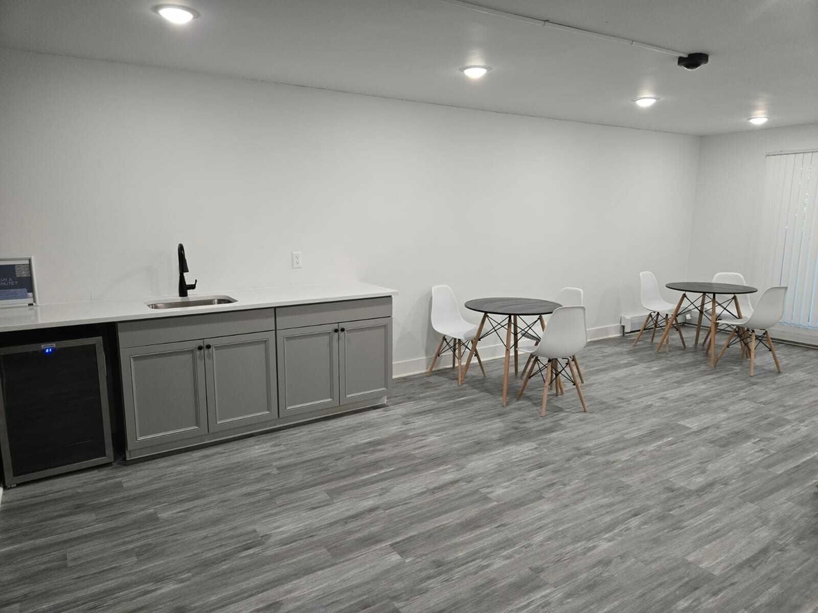 Modern resident lounge with a kitchenette, seating area and dining tables.