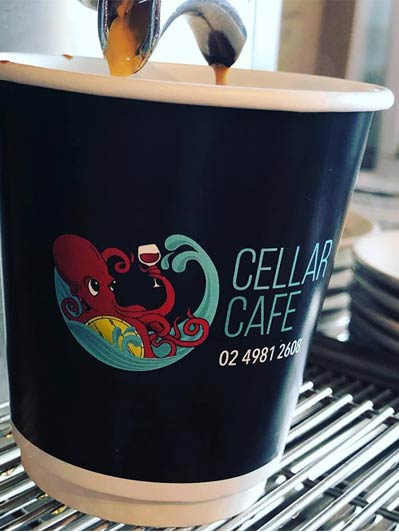 Espresso being poured into a black Cellar Cafe cup with an octopus logo — Café & Bottle Shop Fingal Bay, QLD
