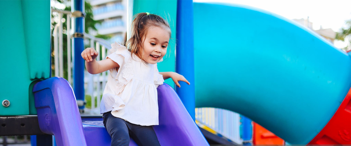 A little girl is playing on a slide at a playground.