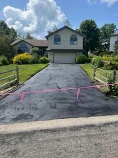 Two-story house with fresh black driveway paving and pink caution tape across the front