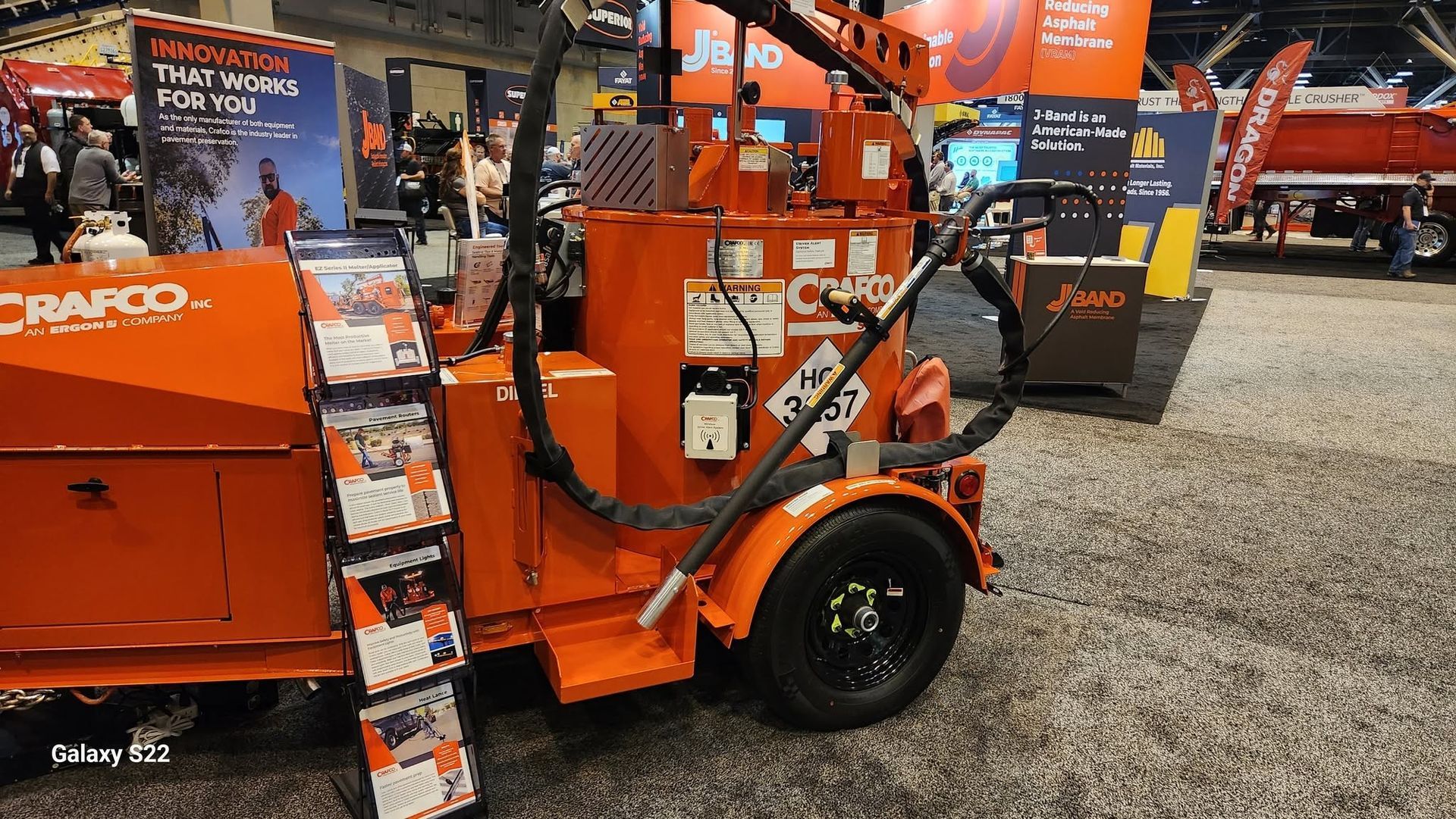 Orange industrial machine on display at an equipment trade show booth.