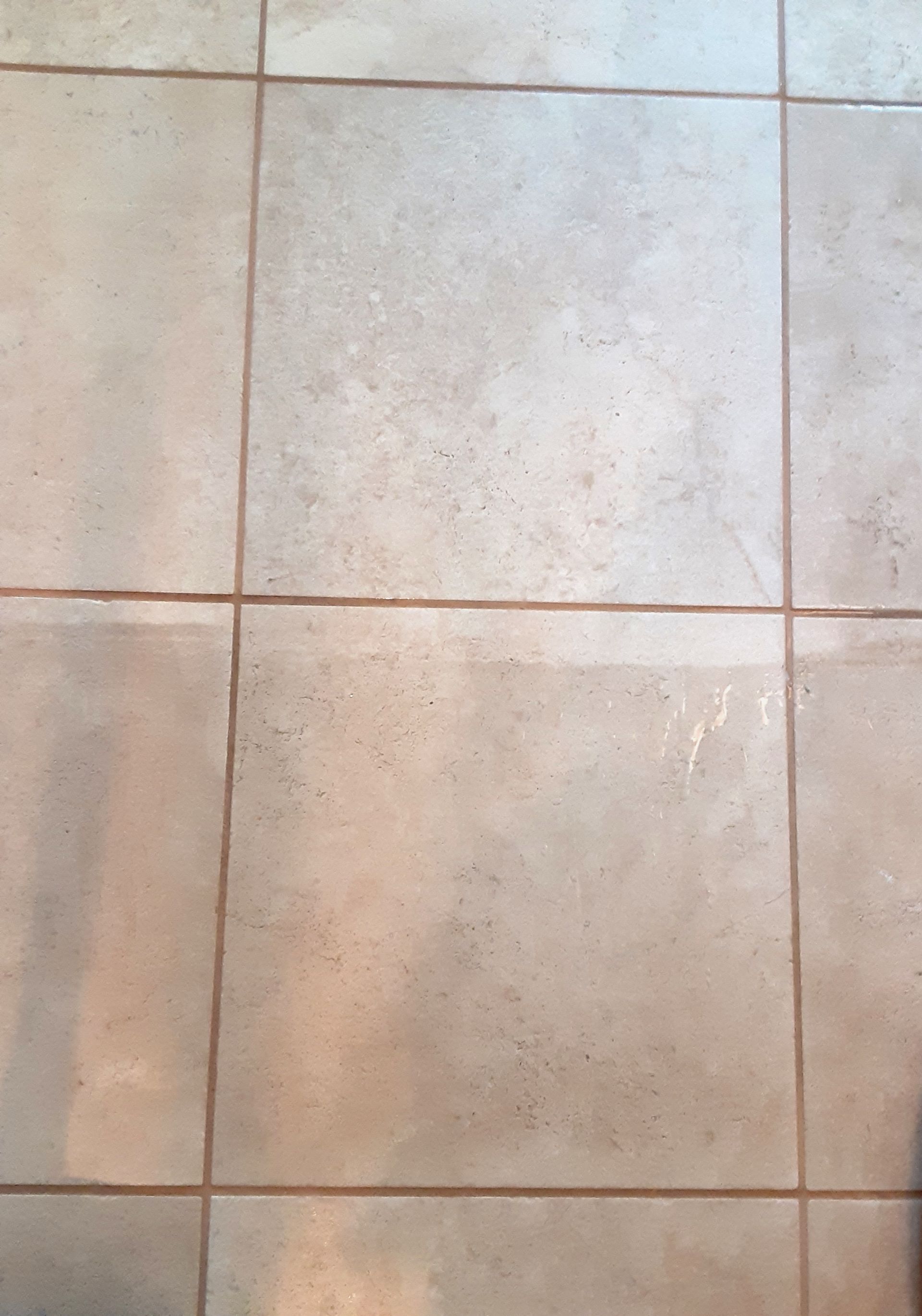 Close-up of light beige tiled floor with brown grout lines.