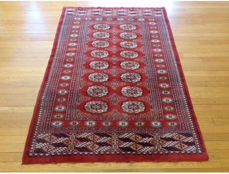 Red oriental rug with central medallions on a hardwood floor.