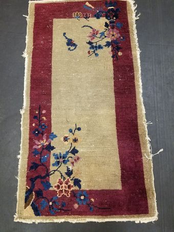 Small rectangular rug with burgundy border, beige center, and floral designs in pink, blue, and burgundy.