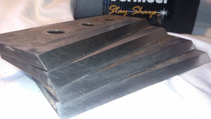 Stacked dark wooden boards with a round hole, resting on a white surface.
