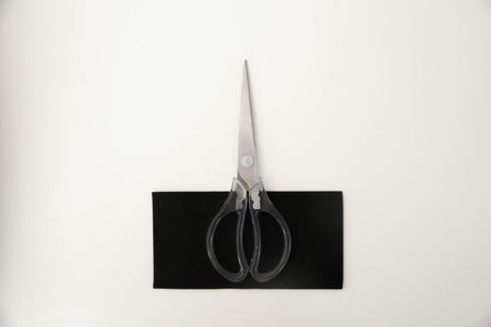 Transparent scissors on a black rectangle against a white background