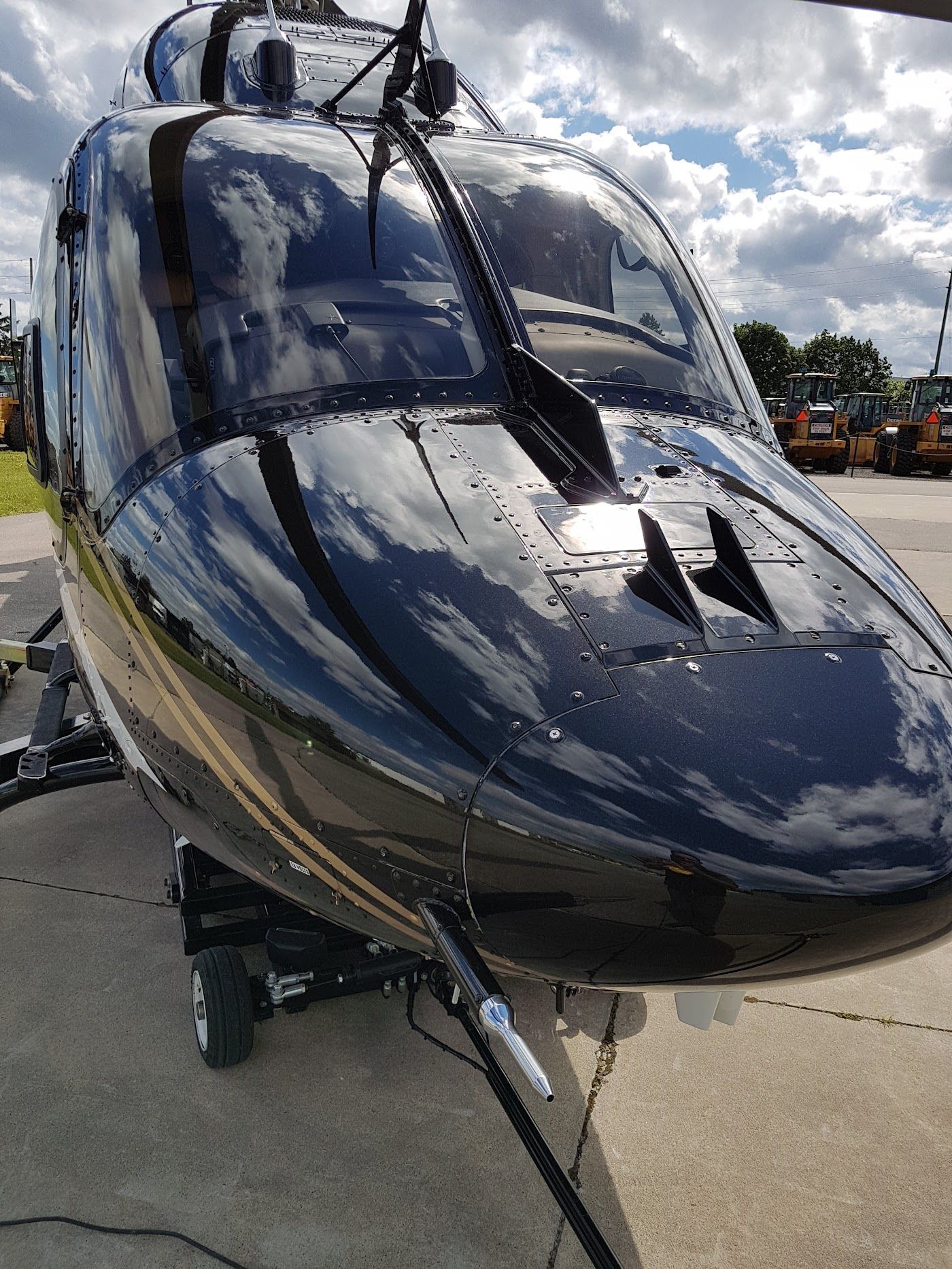Black helicopter with reflective windows on the ground, likely at an airport.