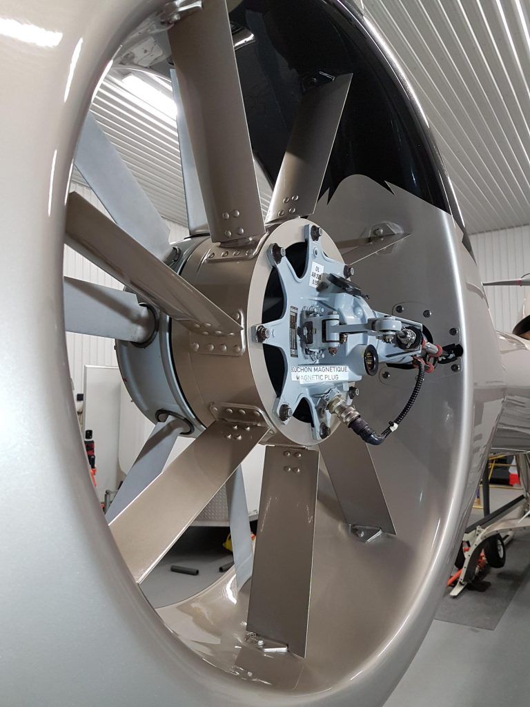 Close-up of a turbofan engine with gray blades. The engine is mounted on a silver aircraft.