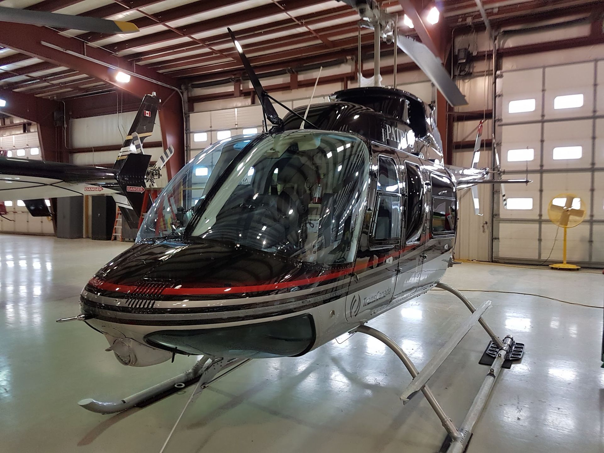 Helicopter inside a hangar with a black and silver exterior, on a light green floor.