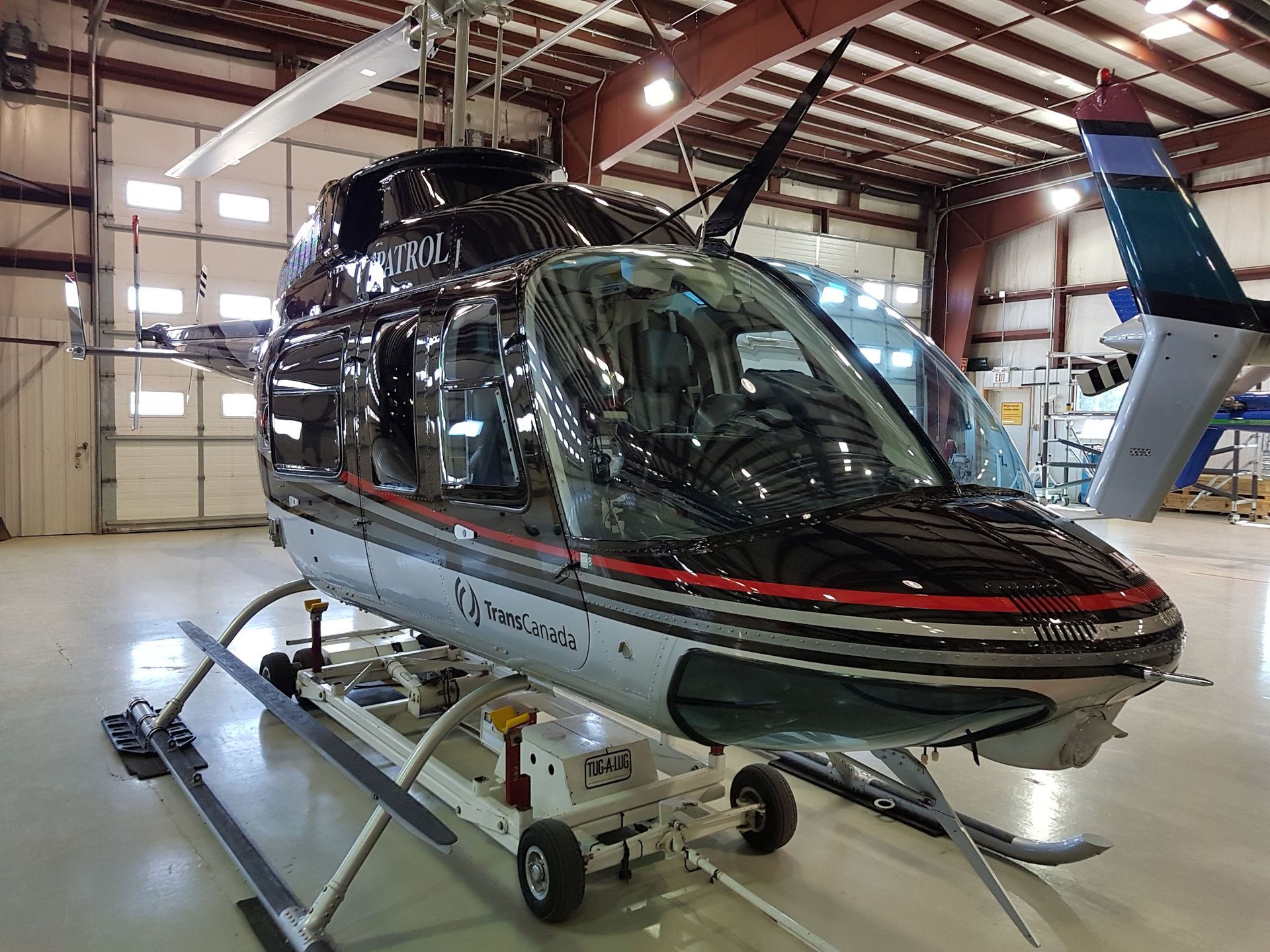 Black and silver helicopter in a hangar, mounted on a wheeled platform.