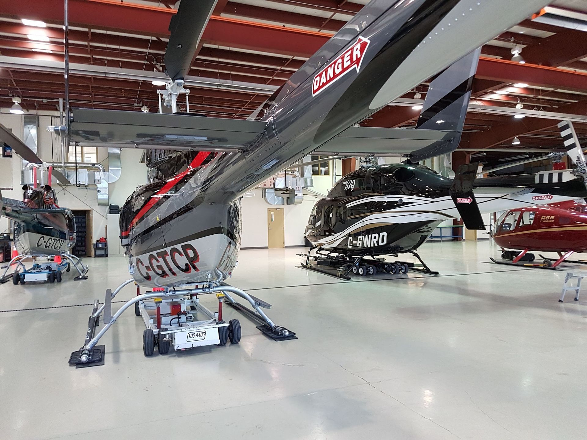 Helicopters in a hangar. A black and gray helicopter,