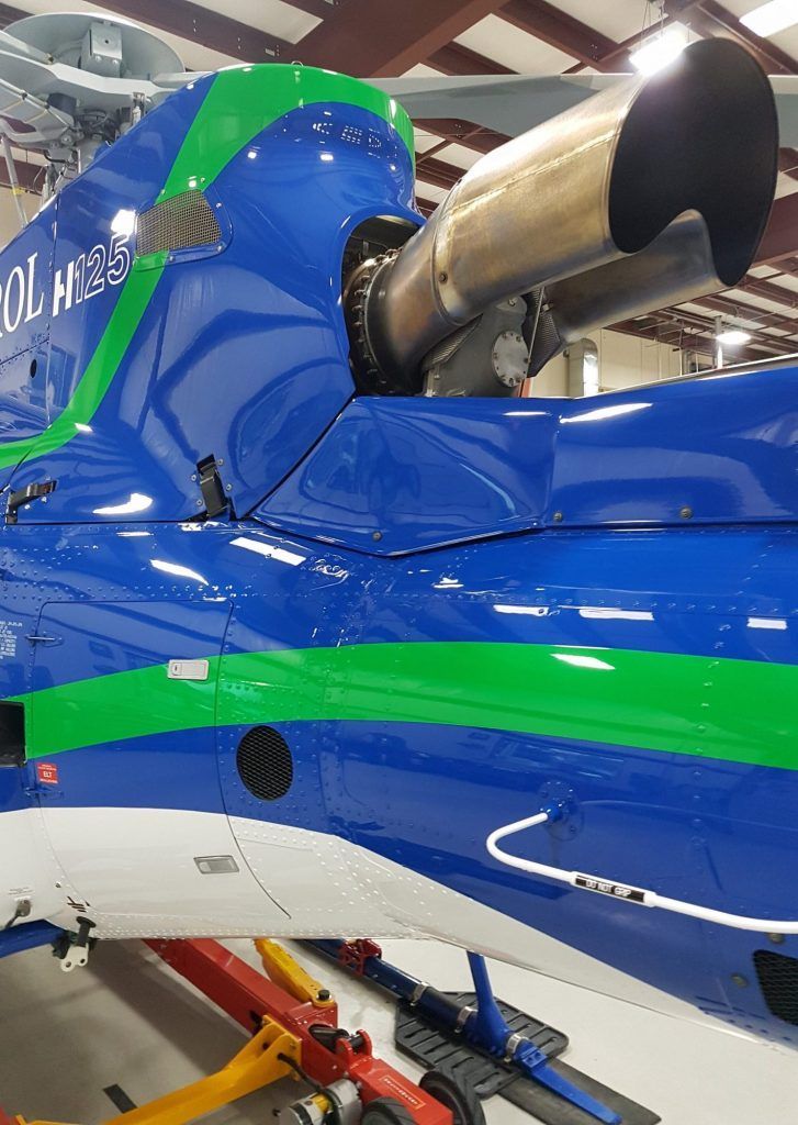 Blue and green helicopter tail section with exhaust, indoors.