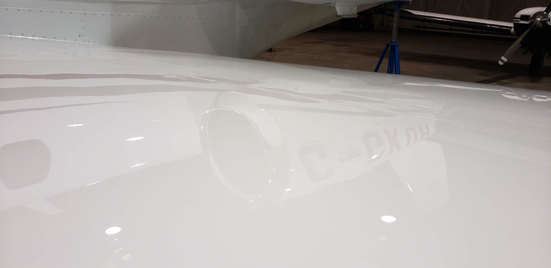 White surface with reflections, possibly an airplane wing.