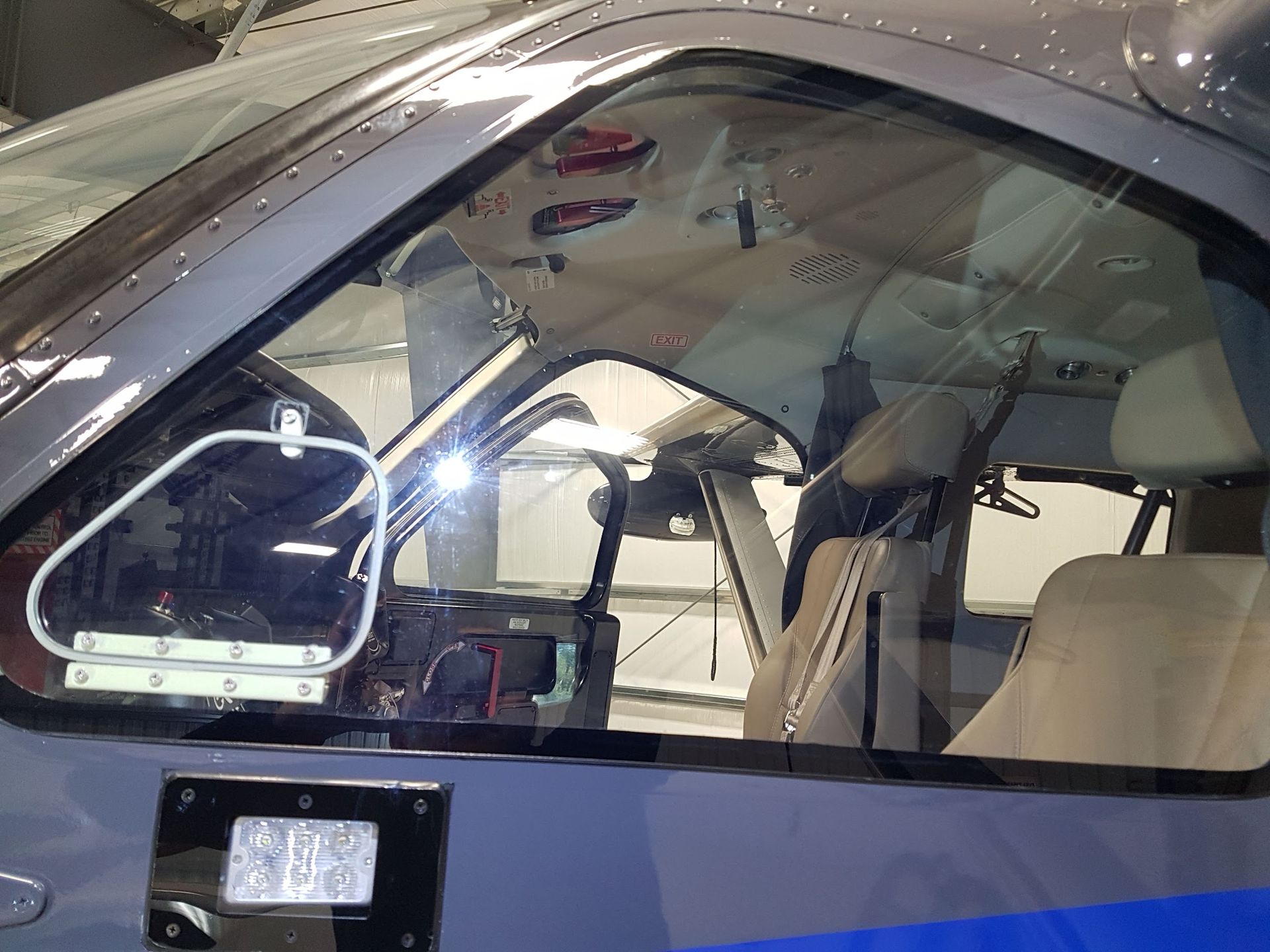Close-up view of helicopter cockpit interior with windshield, seats, and exposed wiring.