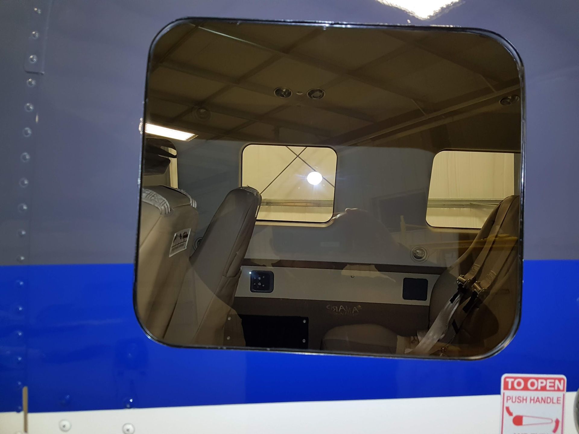 Aircraft cockpit window with a view of interior and controls. Blue and white exterior.