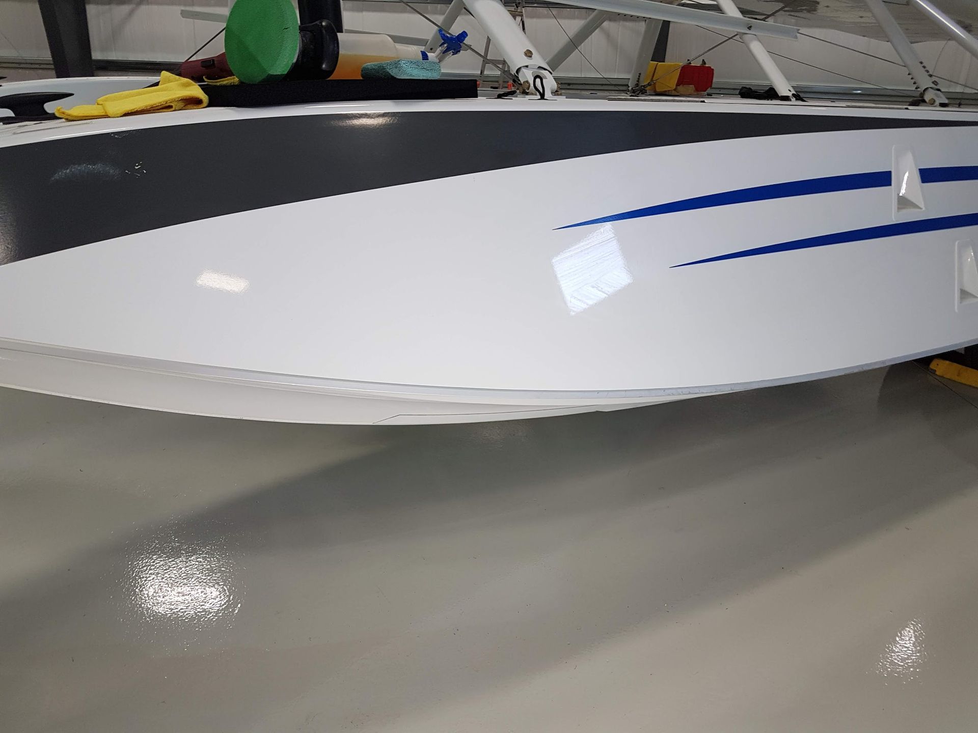 White seaplane float with blue stripes, on a reflective gray floor.